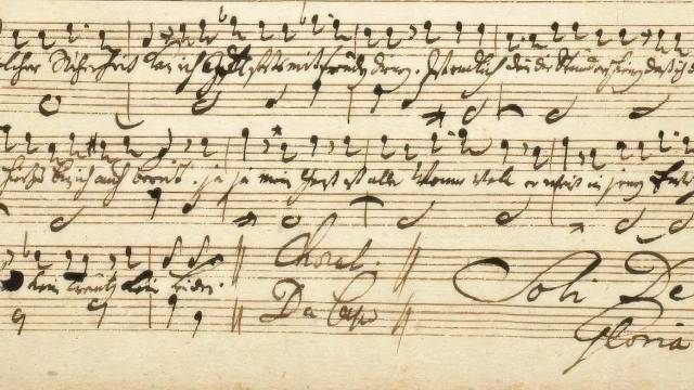 Handschriftliche Noten und Textzeilen auf vergilbtem Notenpapier, historisches Manuskript.